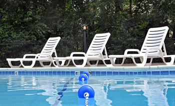 A pool with white chairs and a blue ball in the water